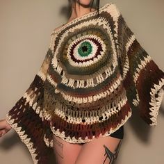 a woman with tattoos wearing a crocheted sweater