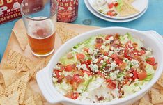 a salad with lettuce, tomatoes and cheese in a bowl next to some tortilla chips