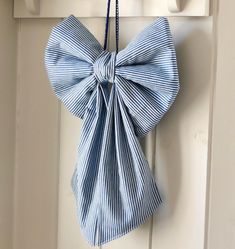 a blue and white striped bow hanging from a hook on a doorknobl