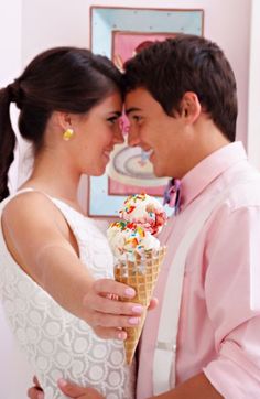 a man and woman standing next to each other holding an ice cream cone