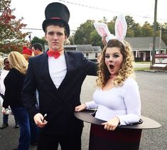 a man and woman dressed up in bunny ears standing next to each other on the street