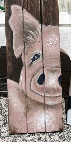 a painting of a pig is shown on a wooden block with another piece of wood in the background