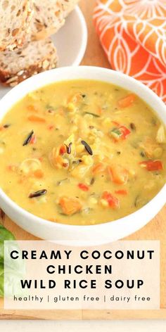 creamy coconut chicken wild rice soup in a white bowl on a cutting board with bread