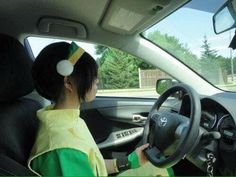 a woman sitting in the driver's seat of a car wearing a yellow and green outfit