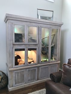 a living room area with a couch, chair and large wooden display cabinet in it