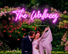 a bride and groom standing under a neon sign