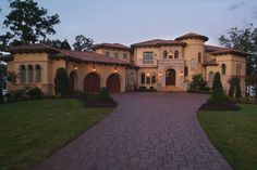 a large house with lots of windows and brick walkway leading up to the front door