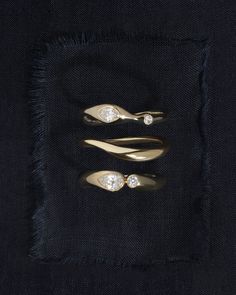 three gold rings sitting on top of a black piece of cloth next to each other