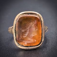 Converted long ago, this wonderful antique cameo ring was once a fob! 9 karat yellow gold surrounds the original element as well as the added shank. A carved carnelian cameo depicts an ancient youth with a strong profile and rather groovy coif! A great unisex ring, and evidence that a single piece of jewelry can take many shapes throughout its history! Details (approximate) Size: 4.5 Weight: 4.06 grams Materials: Gold, Carved Carnelian Metal: 9K yellow gold Marks: None Condition: Very good Antique condition commensurate with age and wear. Small chip on corner. Original element circa 1840, conversion circa latter 19th C. This piece can be resized, resize options are $25 more than the base size. Antique Carnelian Intaglio Rings, Formal Carnelian Cameo Jewelry, Formal Cameo Jewelry In Carnelian, Formal Cameo Carnelian Jewelry, Antique Cameo Signet Ring Collectible, Cameo Ring, Unisex Ring, Single Piece, Rings Statement