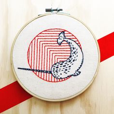 an embroidered hoop with a drawing of a snake in the middle and a red stripe around it