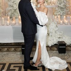 a man and woman standing next to each other in front of a table with candles