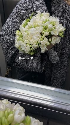 a woman holding a bouquet of flowers in front of a mirror