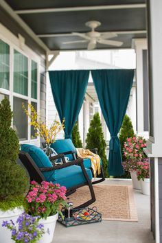 a blue chair sitting on top of a porch next to flowers and potted plants