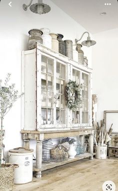 an old white cabinet with glass doors and baskets on it's sides in a living room