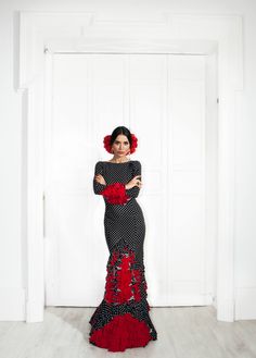 a woman in a black and red dress posing for the camera with her hands on her hips