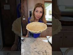 a woman holding up a pie crust on top of a counter