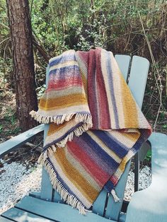 a blanket sitting on top of a blue bench next to a tree in the woods