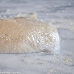 an uncooked piece of bread is wrapped in plastic wrap on the counter top