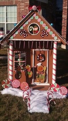 a gingerbread house with candy canes and candies in the front yard, decorated for christmas