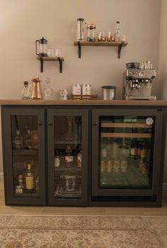 a small bar with bottles and glasses on it's doors, next to a rug