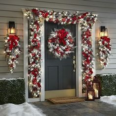 christmas wreaths and lights on the front door of a house