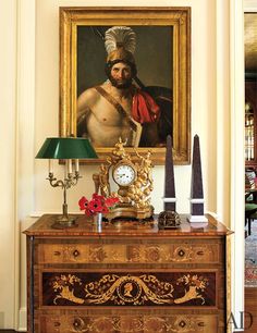 an ornate dresser with a painting on the wall