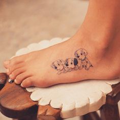 a woman's foot with three puppies on it and one is sitting on top of a stool