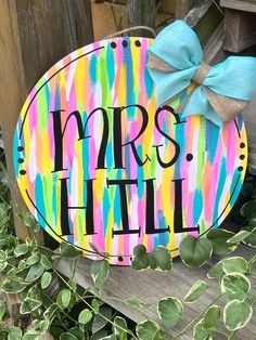 a wooden sign that says mrs hall with a bow on it next to some plants