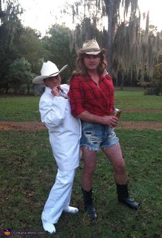 two people dressed up in costumes standing next to each other on the grass with trees in the background