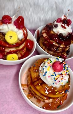 three white bowls filled with waffles covered in toppings and fruit on top