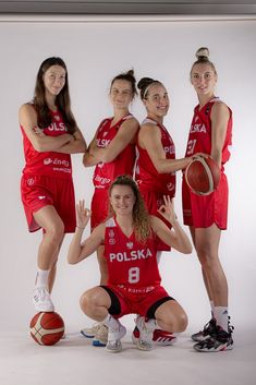 a group of women in red uniforms posing for a photo with a basketball ball and hoop