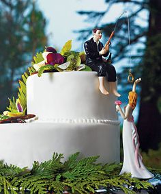 the wedding cake is decorated with figurines and greenery