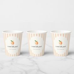 three paper cups sitting on top of a marble counter next to an orange and white striped cup