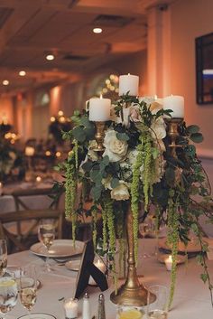 an elegant centerpiece is adorned with greenery and candles