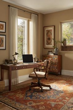 a desk with a laptop computer on top of it in front of two large windows