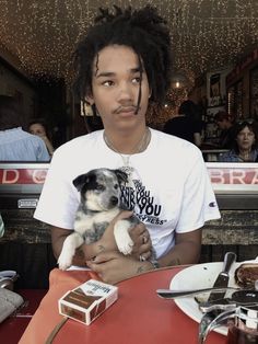 a man sitting at a table holding a small dog