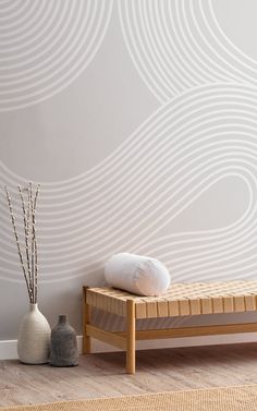 a wooden bench sitting in front of a white wall with wavy designs on it and two vases next to it