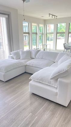 a large white couch sitting in the middle of a living room next to two windows