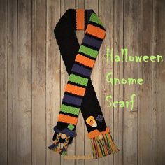 a knitted halloween scarf hanging on a wooden wall with the words halloween gnome scarf