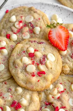 cookies with white chocolate chips and strawberries are arranged on a plate, ready to be eaten