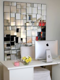 an apple computer sitting on top of a desk next to a vase with yellow flowers