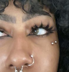 a close up of a person with piercings on her nose and nose ring in front of their face