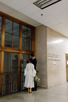 a man and woman standing in front of a building with glass doors on both sides