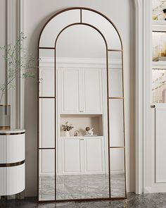 an arched mirror in the corner of a room with white walls and marble flooring