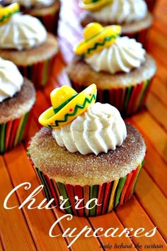 cupcakes with white frosting and decorations on top are sitting on a wooden table