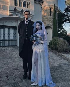 a man and woman dressed up as corpse brides in front of a large house