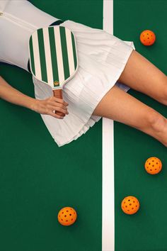 a woman laying on top of a tennis court next to oranges