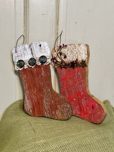 two wooden christmas stockings sitting on top of a green pillow