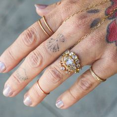 a woman's hand with tattoos and rings on it