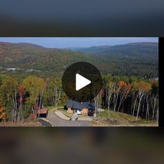 an aerial view of a house surrounded by trees in the fall with mountains in the background